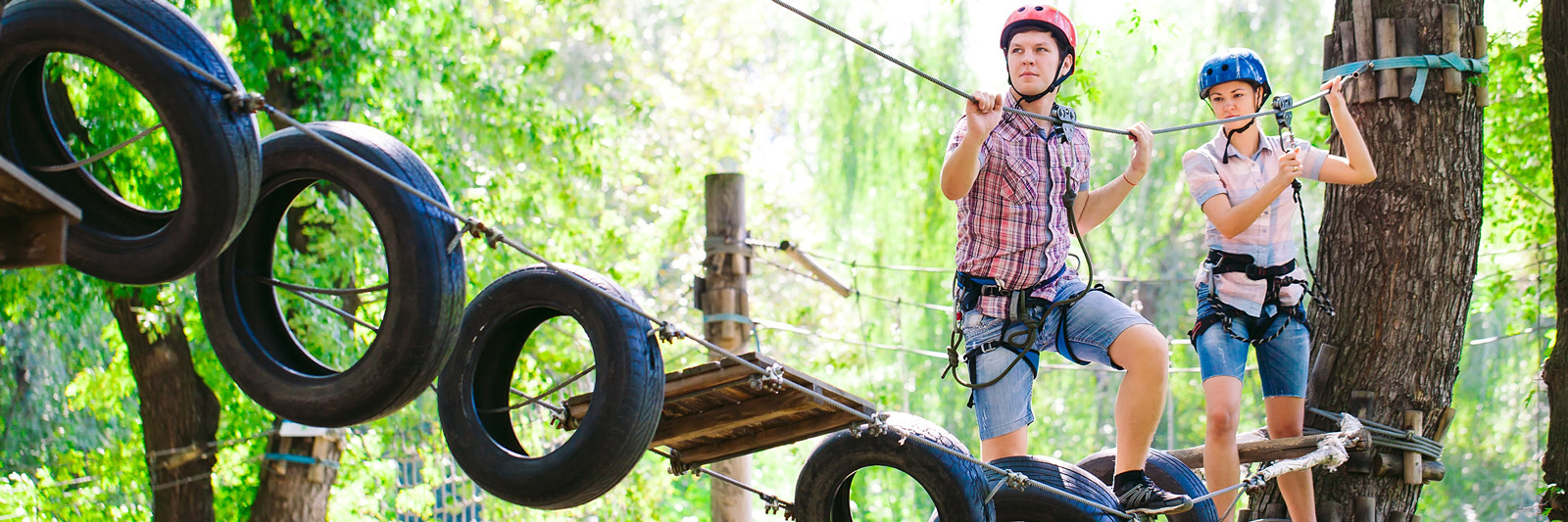 a boy and girl navigating a high rope bridge